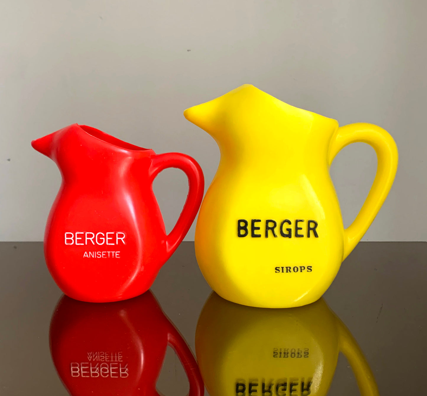 A Pair of Vintage French Berger Anisette & Sirops Red & Yellow Plastic Jugs