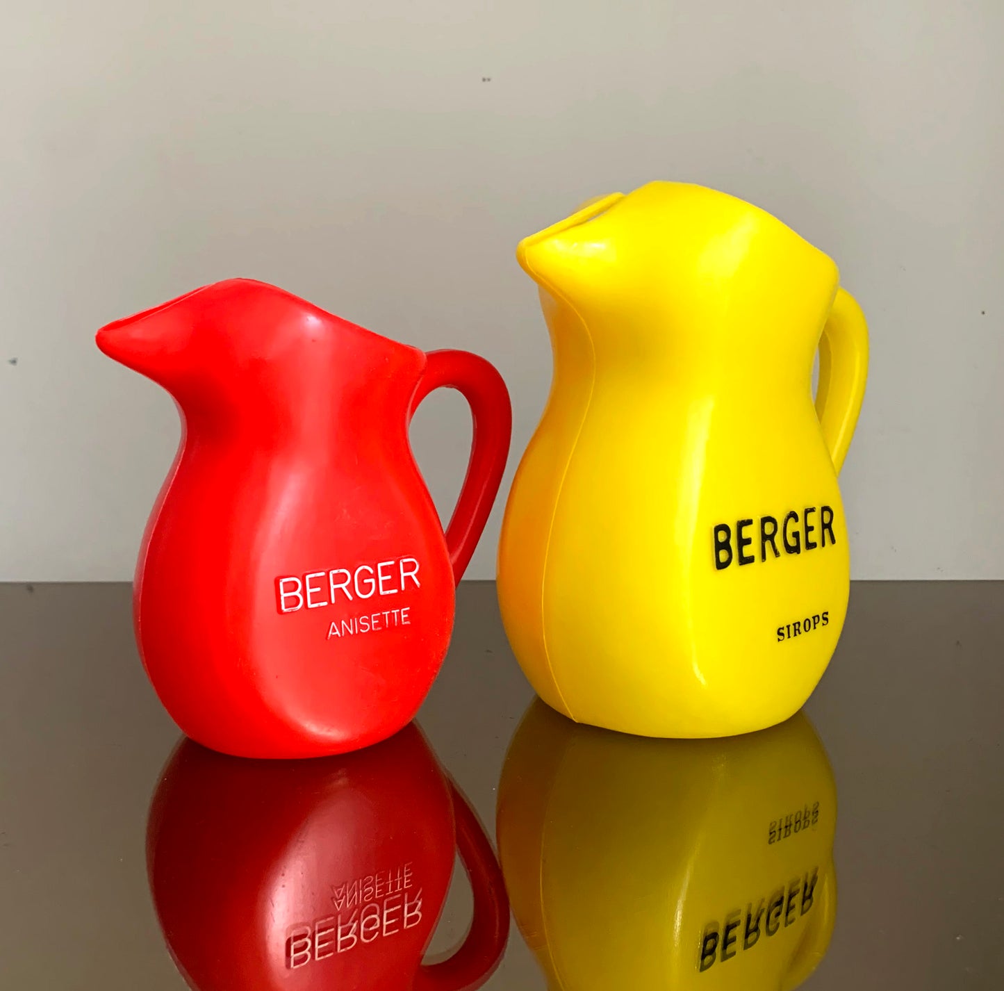 A Pair of Vintage French Berger Anisette & Sirops Red & Yellow Plastic Jugs